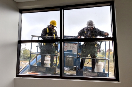 Three The Exterior Group technicians on separate ladders, cleaning upper-story windows. 