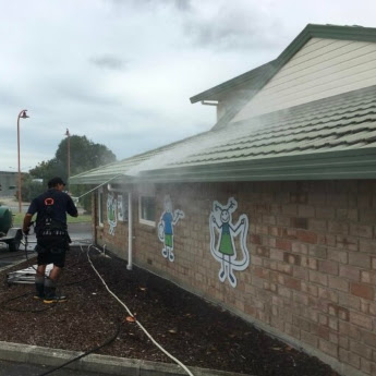 A The Exterior Group technician using a professional-grade pressure washer.